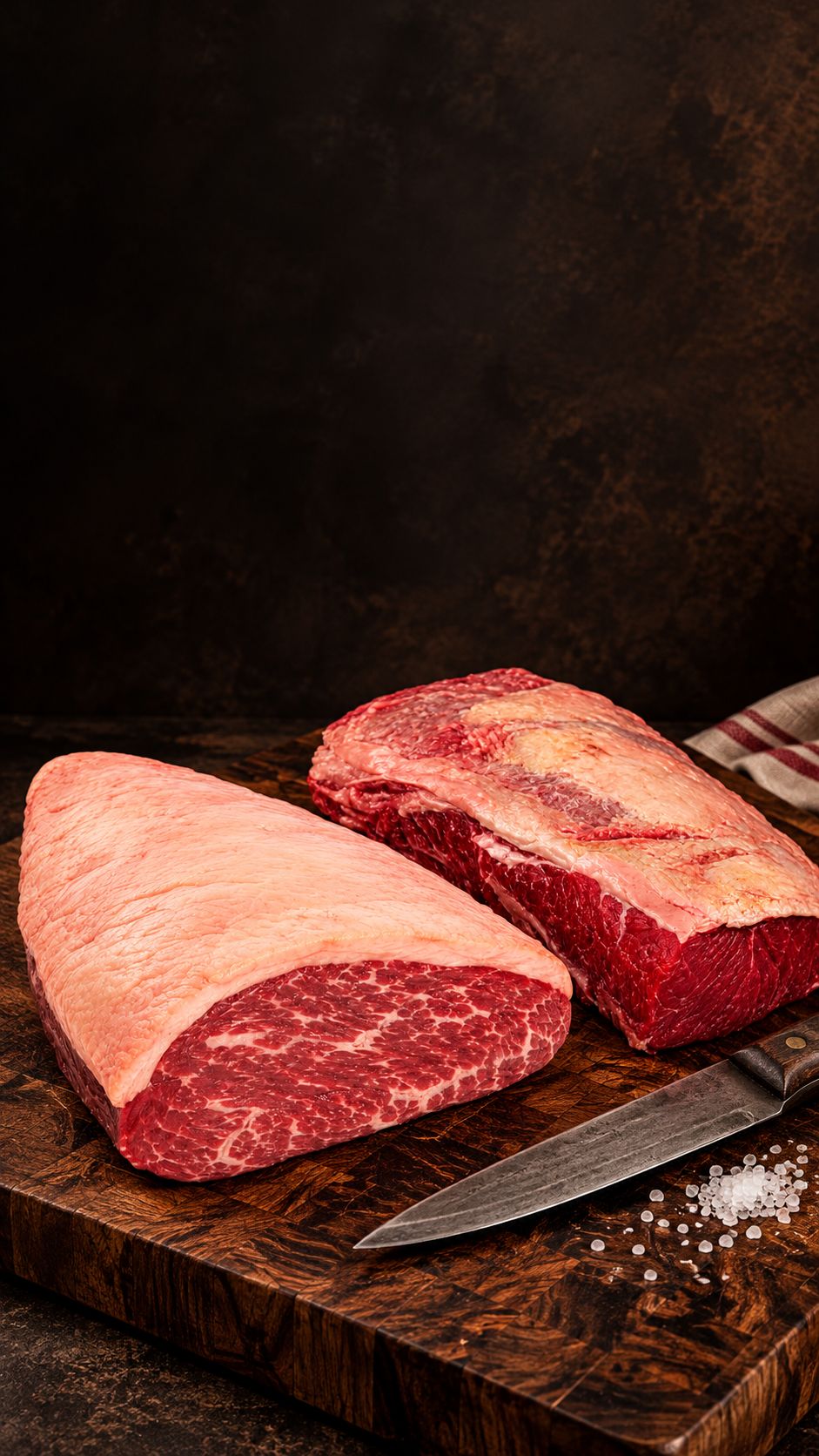 Picanha e contrafilé inteiros sobre tábua de madeira escura